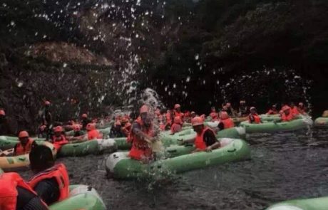 SKD employees wearing orange helmets and life jackets in green rafts exhibiting company culture
